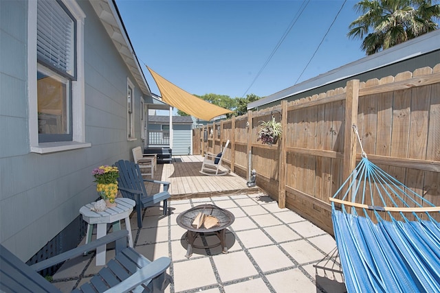 view of patio with a wooden deck, a fire pit, and fence