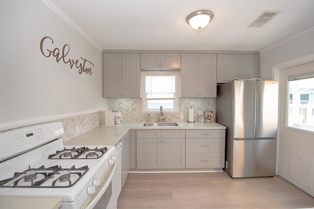kitchen featuring a sink, freestanding refrigerator, white range with gas cooktop, visible vents, and gray cabinetry
