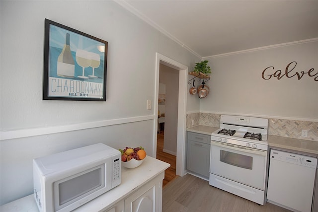 kitchen featuring light wood-style flooring, crown molding, white appliances, light countertops, and tasteful backsplash