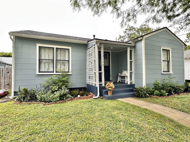 ranch-style house featuring a porch, fence, and a front lawn