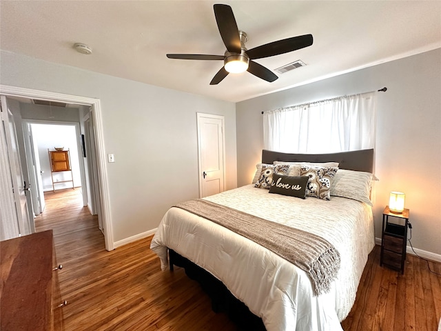 bedroom with baseboards, a ceiling fan, visible vents, and wood finished floors