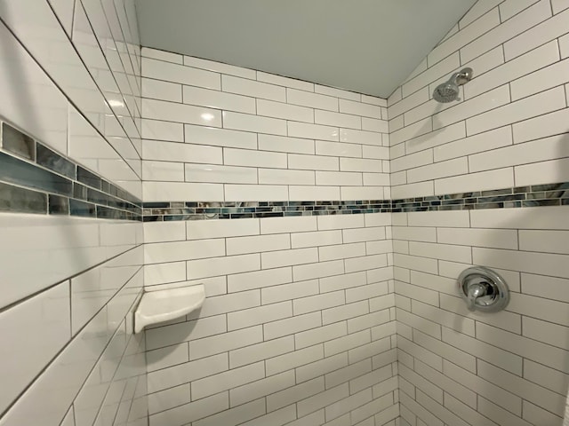 bathroom featuring vaulted ceiling and tiled shower