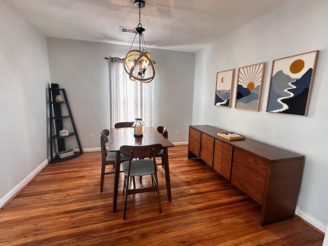 dining area with baseboards, an inviting chandelier, and wood finished floors