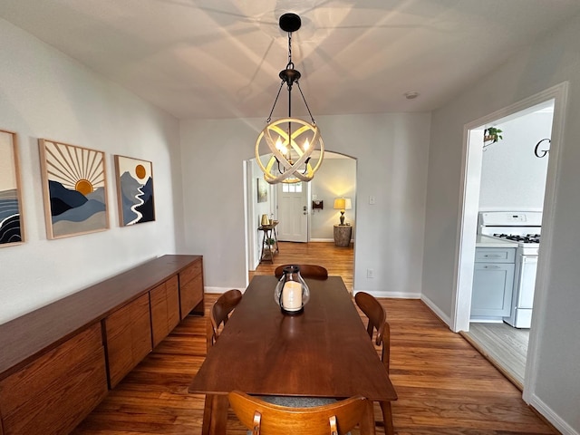 dining area featuring a chandelier, dark wood-type flooring, and baseboards