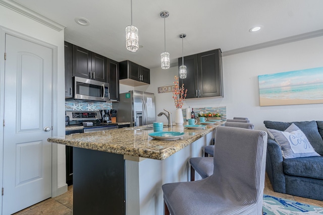 kitchen featuring a sink, open floor plan, appliances with stainless steel finishes, a kitchen bar, and light stone counters