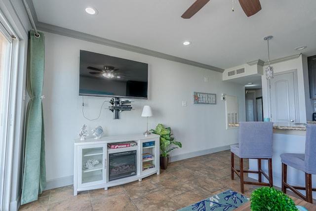 living area featuring stone finish floor, ornamental molding, a ceiling fan, visible vents, and baseboards