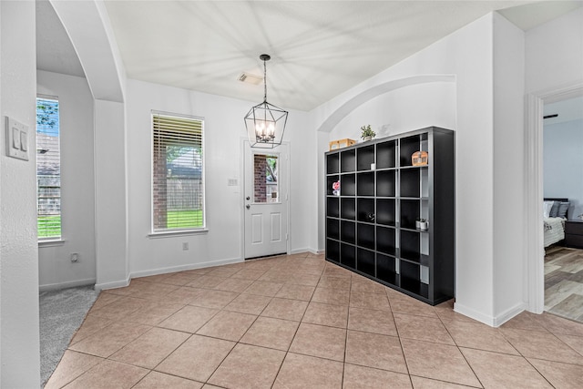 entryway featuring tile patterned flooring, an inviting chandelier, baseboards, and visible vents