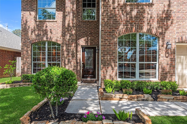 entrance to property featuring brick siding and a yard