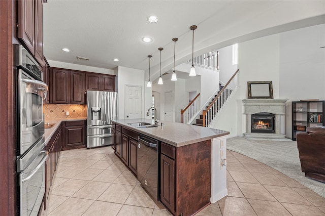kitchen with a sink, appliances with stainless steel finishes, light tile patterned flooring, open floor plan, and recessed lighting
