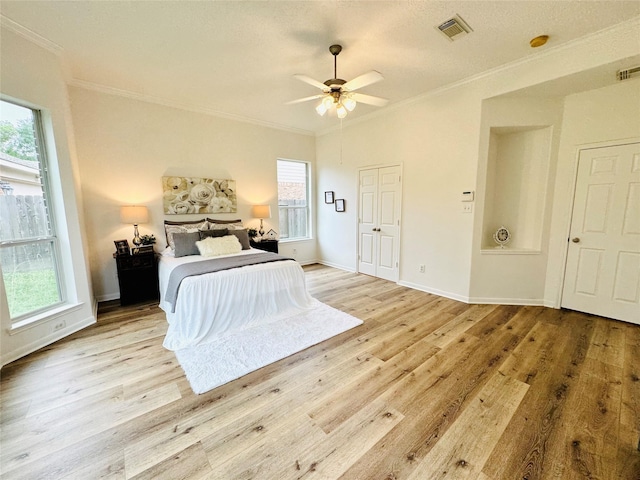 bedroom featuring crown molding, wood finished floors, baseboards, and visible vents