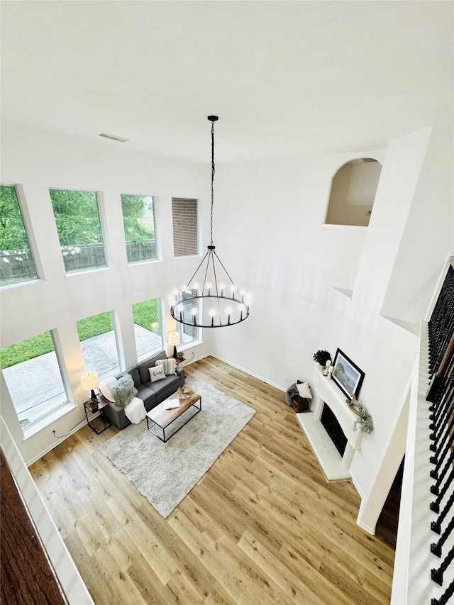 living area featuring wood finished floors, visible vents, a notable chandelier, and a fireplace with raised hearth