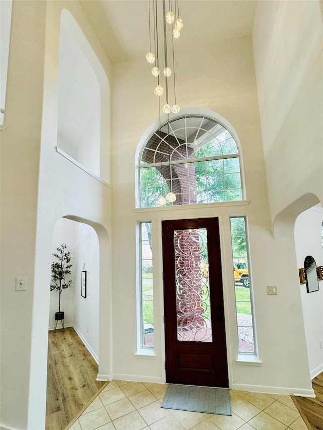 entryway featuring arched walkways, a towering ceiling, and a wealth of natural light