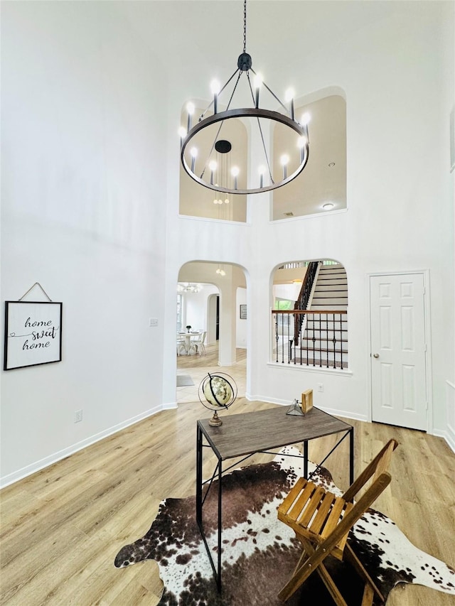 interior space featuring arched walkways, a high ceiling, an inviting chandelier, and wood finished floors