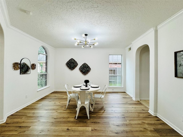 dining room featuring crown molding, arched walkways, and an inviting chandelier