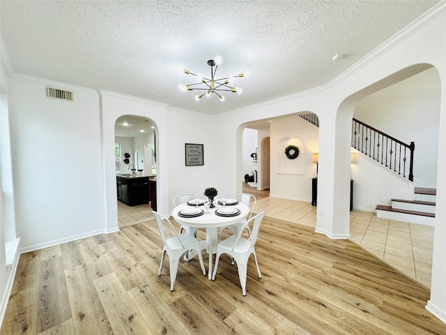dining area with arched walkways, visible vents, a textured ceiling, and wood finished floors