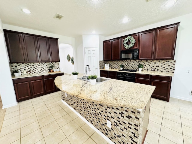 kitchen featuring visible vents, light tile patterned floors, arched walkways, a sink, and black appliances