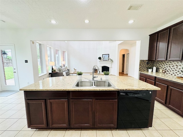 kitchen with arched walkways, black dishwasher, a sink, open floor plan, and an island with sink