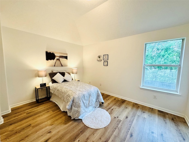 bedroom featuring wood finished floors, baseboards, and lofted ceiling