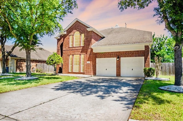 traditional-style house with a yard, fence, a garage, and concrete driveway