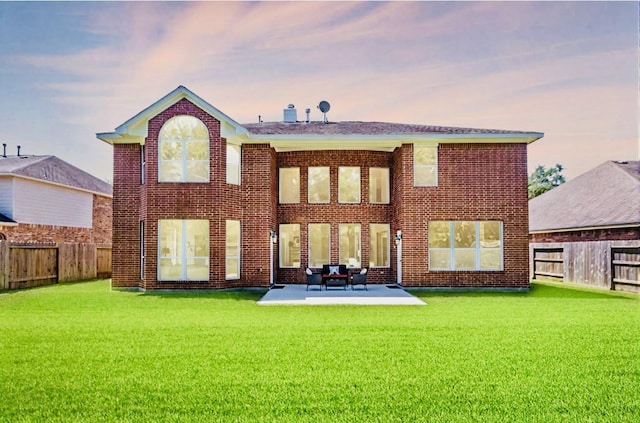 back of house at dusk featuring a patio, a fenced backyard, and a lawn