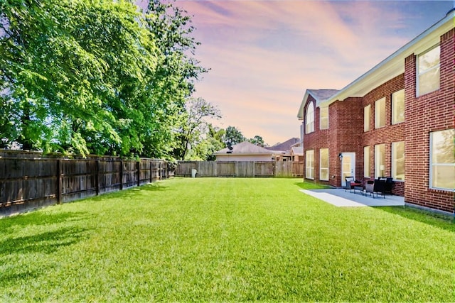 yard at dusk with a patio area and a fenced backyard