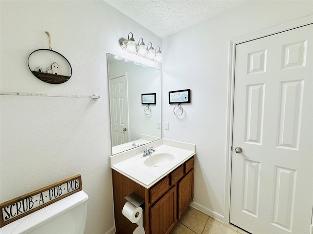 half bath with a textured ceiling, vanity, toilet, tile patterned floors, and baseboards