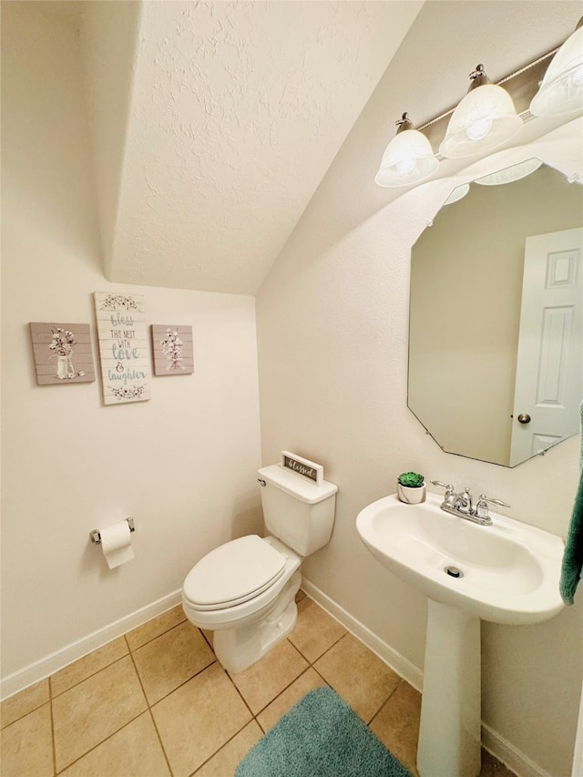 bathroom with baseboards, vaulted ceiling, tile patterned floors, a textured ceiling, and toilet