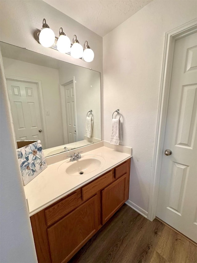 bathroom featuring baseboards, vanity, wood finished floors, and a textured ceiling