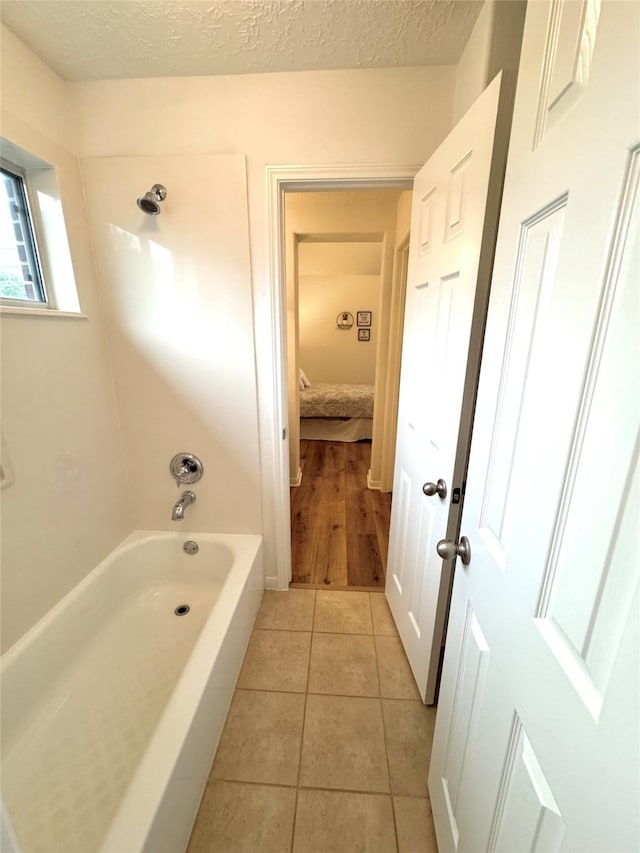 bathroom featuring a textured ceiling, tile patterned flooring, and tub / shower combination
