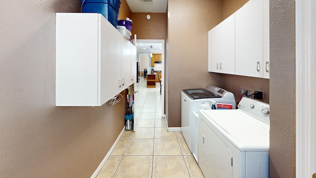laundry area with baseboards, light tile patterned floors, washing machine and dryer, visible vents, and cabinet space