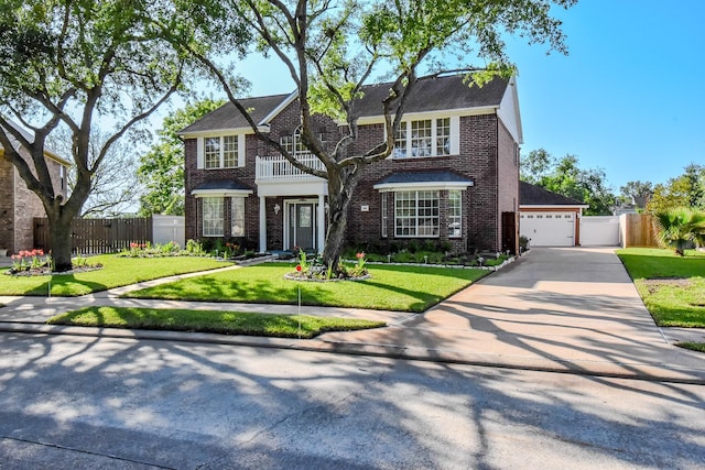 english style home featuring a front yard, brick siding, a balcony, and fence
