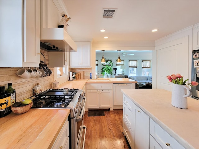 kitchen with visible vents, wooden counters, white cabinetry, stainless steel gas stove, and backsplash