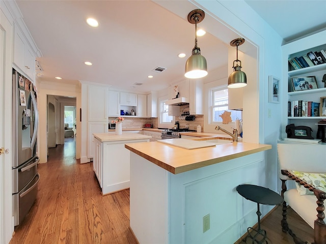 kitchen featuring a peninsula, visible vents, appliances with stainless steel finishes, under cabinet range hood, and a sink