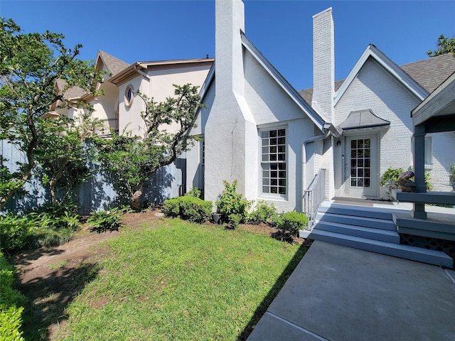 exterior space with a front yard, stucco siding, and a chimney