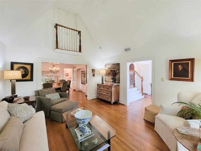living room with visible vents, a chandelier, stairway, light wood finished floors, and high vaulted ceiling