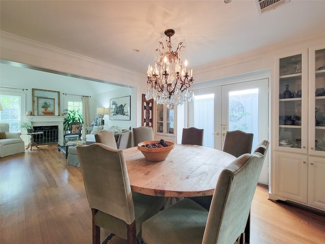 dining space featuring visible vents, an inviting chandelier, a wealth of natural light, crown molding, and french doors