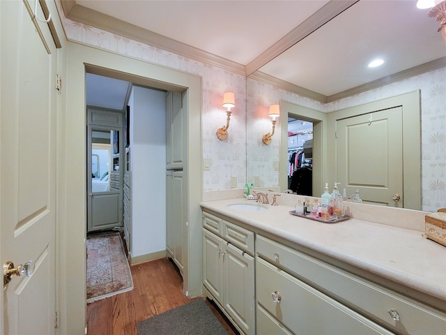 bathroom with crown molding, vanity, wood finished floors, and wallpapered walls