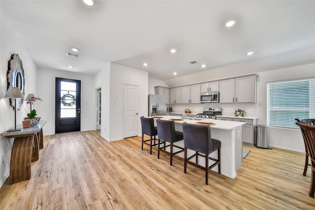 15415 Surrey Pines Ln, Houston, TX 77044 - kitchen featuring stainless steel appliances, gray cabinetry, light countertops, a breakfast bar, and an island with sink