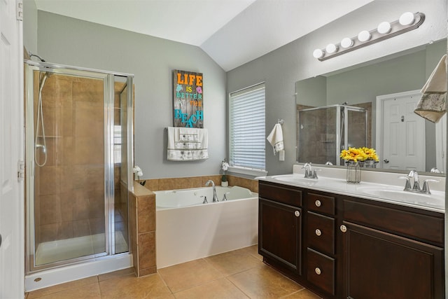 bathroom with lofted ceiling, double vanity, tile patterned flooring, a stall shower, and a garden tub