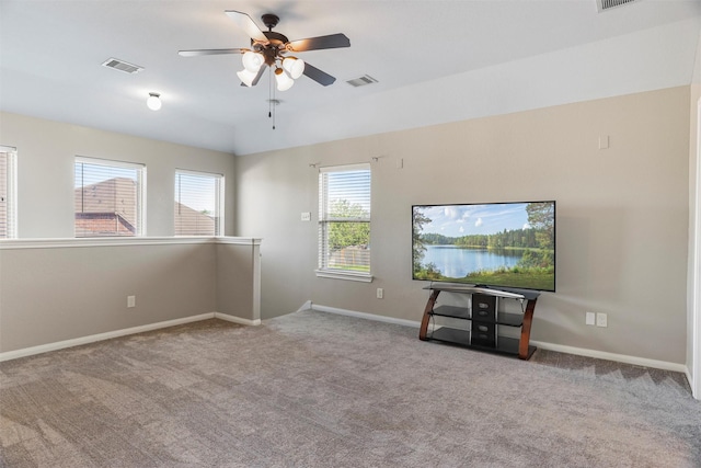 carpeted empty room featuring visible vents, a ceiling fan, and a healthy amount of sunlight