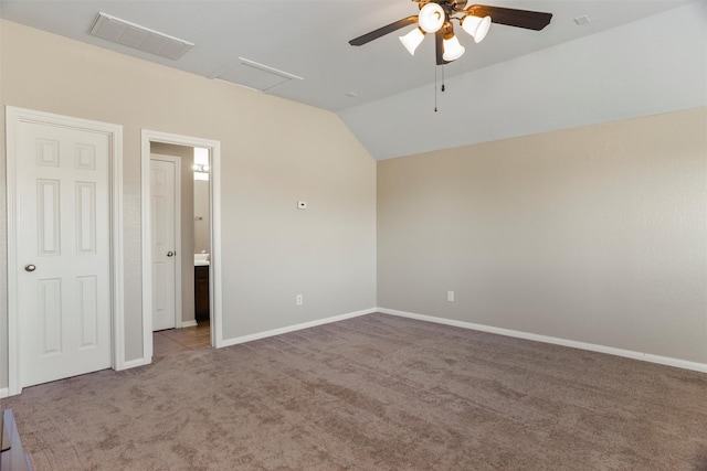 carpeted spare room with baseboards, visible vents, vaulted ceiling, and a ceiling fan