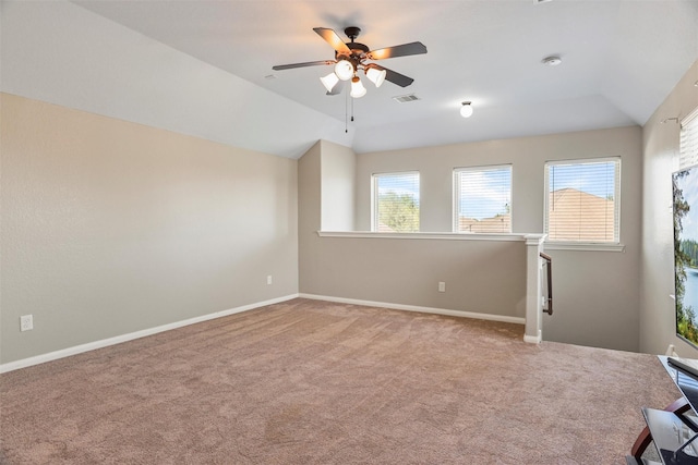 spare room featuring visible vents, baseboards, a ceiling fan, vaulted ceiling, and carpet flooring