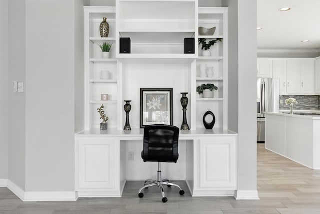 home office featuring built in desk, light wood finished floors, baseboards, recessed lighting, and built in features