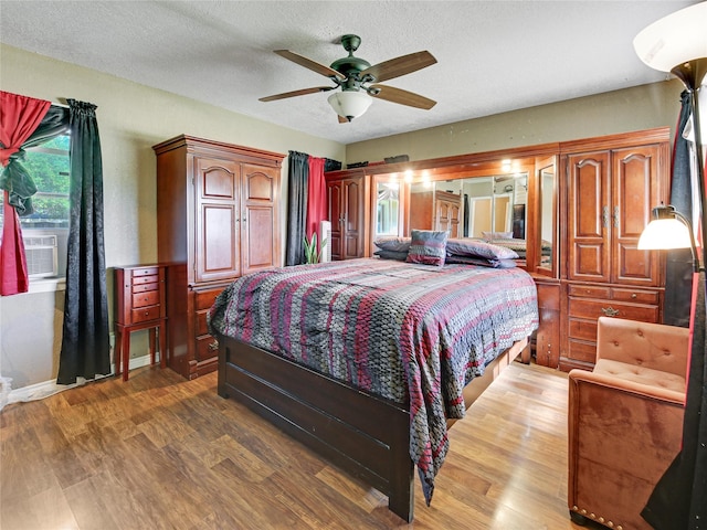 bedroom with ceiling fan, cooling unit, a textured ceiling, and wood finished floors