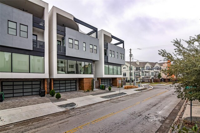 view of building exterior featuring an attached garage, driveway, and a residential view