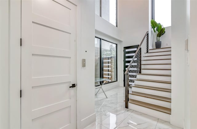 entrance foyer featuring stairway and marble finish floor