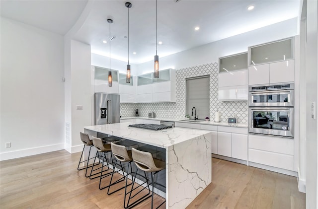 kitchen featuring a center island, a sink, modern cabinets, white cabinetry, and appliances with stainless steel finishes