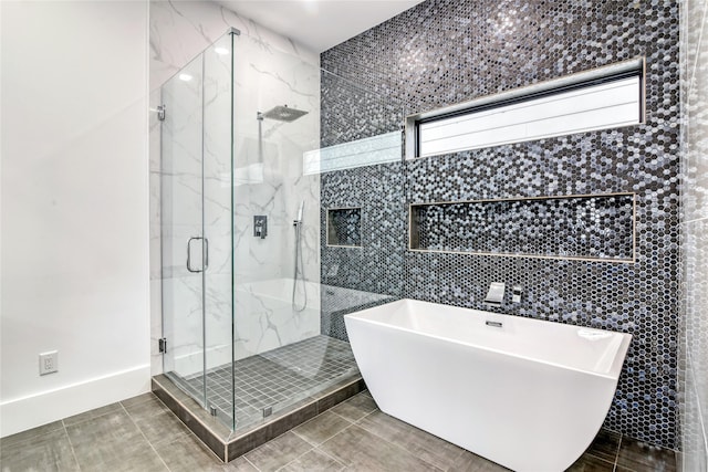 full bathroom with a freestanding bath, tile patterned floors, a marble finish shower, and tile walls