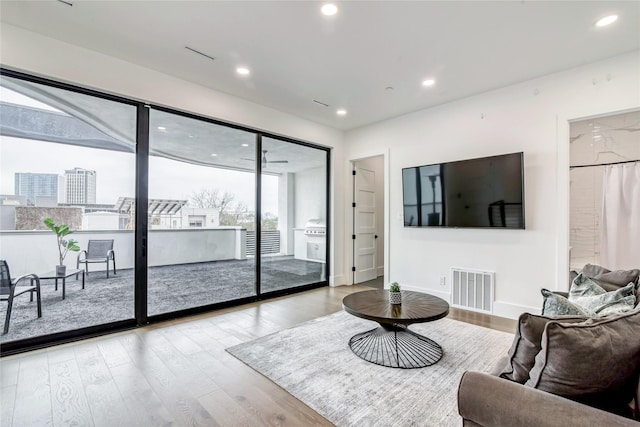 living area with baseboards, wood finished floors, visible vents, and recessed lighting