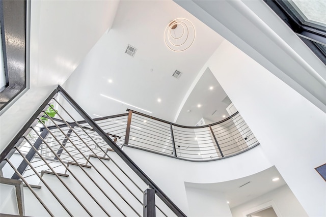 stairs with a towering ceiling, visible vents, and recessed lighting